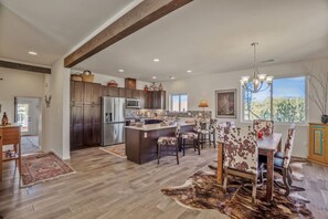 A spacious kitchen with a central island, dark wooden cabinets, stainless steel appliances, and a dining area with a cowhide rug and patterned chairs. - Casa Bella - Hot tub, well equipped and mountain views (Santa Fe)