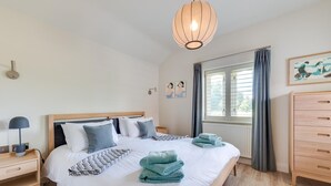 A bedroom with a large bed, a bedside table with a lamp, a wooden dresser, and a window with curtains. - 2 Bed in Middleton (oc-rfb) (Middleton Moor)
