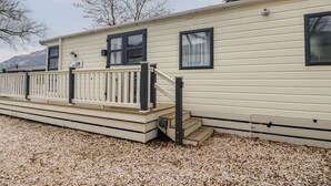 A mobile home with a deck, a small staircase, and a window. - Loch Lomond Holiday Home (Arrochar)