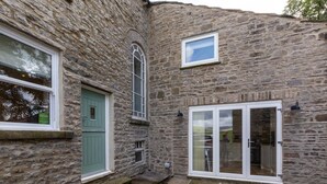 A stone building with a green door, a window, and a door with glass panels. - 4 Bed in Gayle (oc-ds950) (Hawes)
