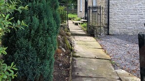 A stone building with a narrow pathway leading to a gated entrance. - 4 Bed in Gayle (oc-ds950) (Hawes)