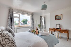 A bedroom with a large bed, a wooden dresser, a desk, and a window with curtains. - 4 Bed in Whitby (oc-w466) (Whitby)