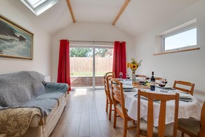 A cozy dining area with a table set for two, a sofa, and a painting on the wall. - 4 Bed in Whitby (oc-w466) (Whitby)