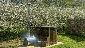 Ein tragbarer Grill für den Außenbereich mit Schornstein, einem Whirlpool und einer Holzterrasse in einem Garten.