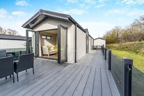 A modern building with a deck, a sofa, and a table. - 2 Bed in Oulton Broad (oc-m31734) (Oulton Broad)