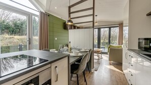 Cozinha moderna com uma ilha grande, área de jantar com cadeiras e vista para o exterior.