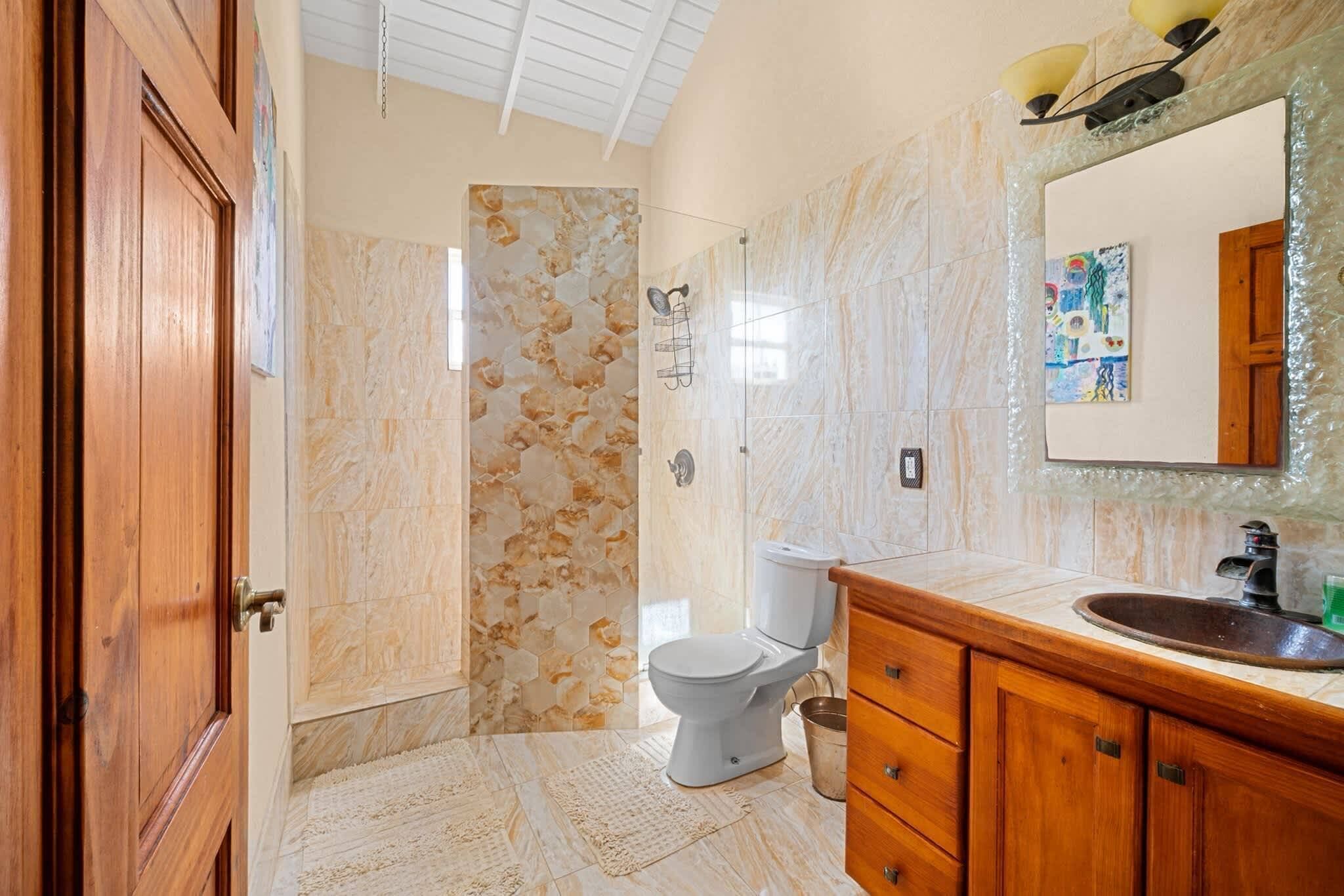 A bathroom with a marble floor, a wooden vanity, a sink, and a toilet.