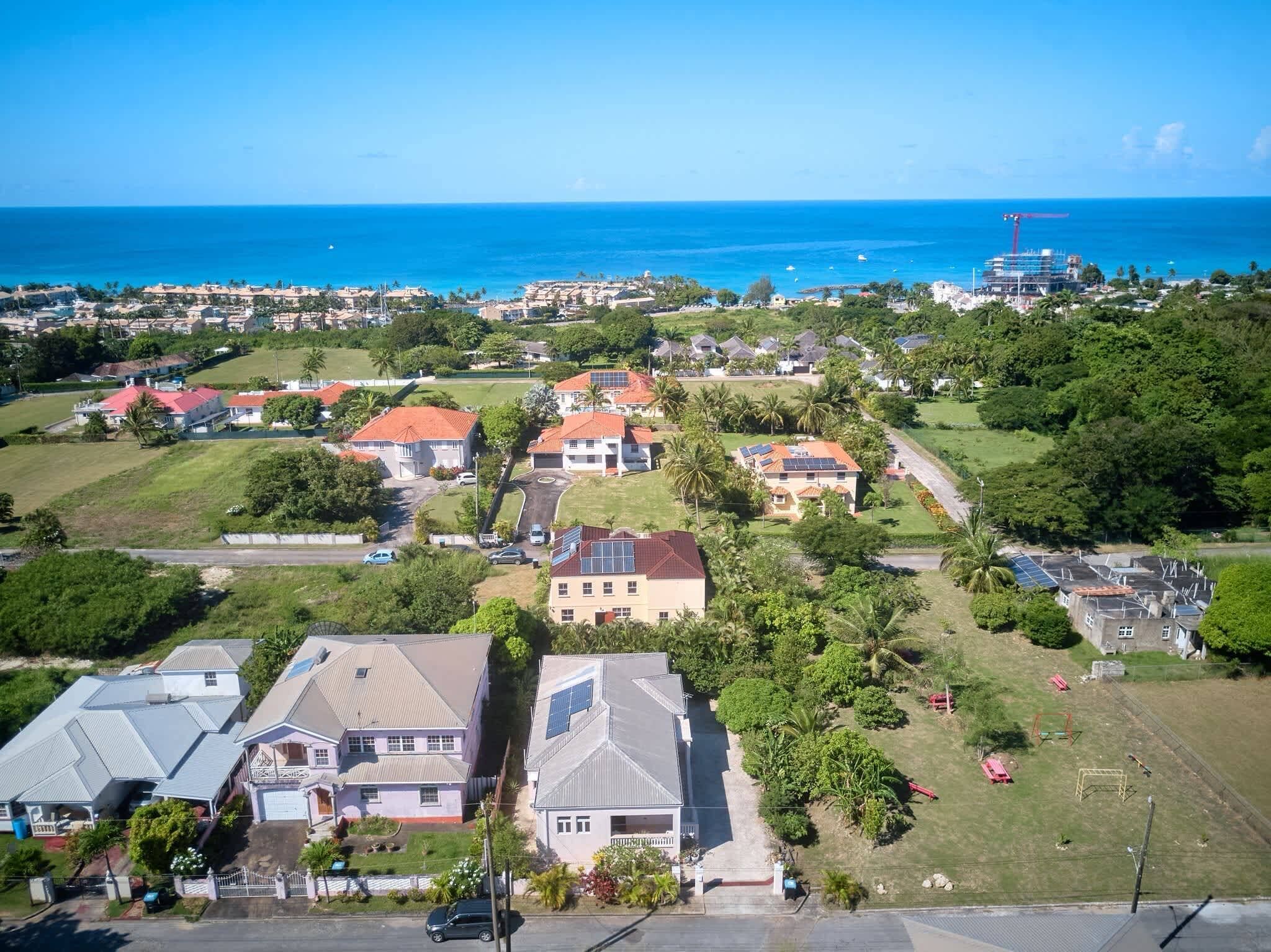 A residential area with houses, solar panels, and a view of the ocean.
