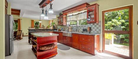 A spacious kitchen with a large island, wooden cabinets, and a sliding glass door to the outdoors.