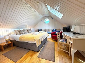 Ein Schlafzimmer mit Bett, Schreibtisch, Stuhl und einem Dachfenster.