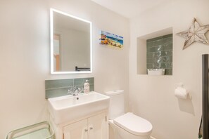 Ein Badezimmer mit einem weißen Waschbecken, einer Toilette, einem Spiegel und einem dekorativen Stern an der Wand.