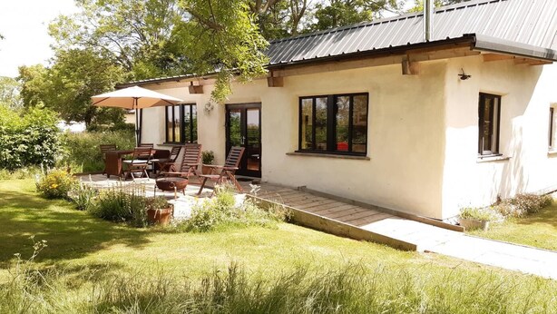 Et toetagers hus med en patiohave, der indeholder et bord og stole, omgivet af en have.