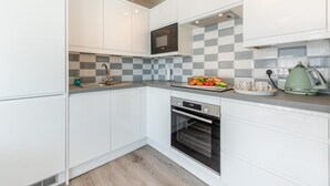 Une cuisine moderne avec des meubles blancs, un four à micro-ondes, un four traditionnel et un pare-feu à carreaux.