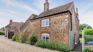 A stone house with a tiled roof, a small front garden, and a gravel driveway. - 2 Bed in Heacham (oc-2013) (Heacham)