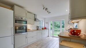 A modern kitchen with white cabinets, stainless steel appliances, and a wooden countertop. - 4 Bed in Walberswick (oc-4ms) (Walberswick)