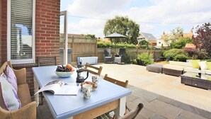 Eine Terrasse mit Esstisch, Outdoor-Möbeln und Blick auf den Garten.
