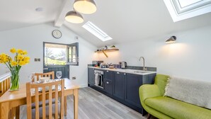 Ett modernt kök med en matplats, en grön soffa och ett matbord med stolar.