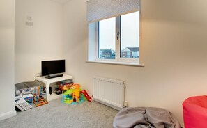 A child's play area with a TV, toys, and a window with a view of houses. - 4 Bed in Beadnell (oc-gd1280) (Beadnell)