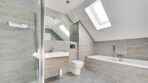 A modern bathroom with a shower, toilet, and sink, featuring a skylight and a view of a staircase. - 4 Bed in Beadnell (oc-gd1280) (Beadnell)