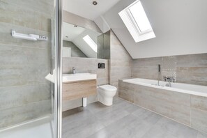 A modern bathroom with a shower, toilet, and sink, featuring a skylight and a view of a staircase. - 4 Bed in Beadnell (oc-gd1280) (Beadnell)