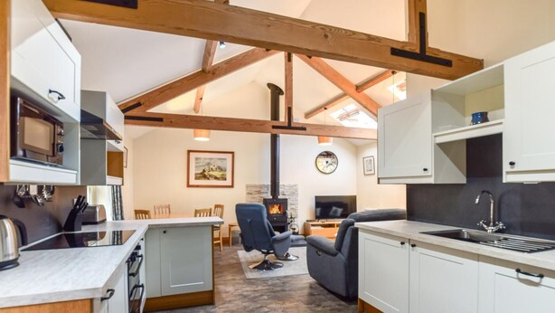 A modern kitchen with a dining area, a fireplace, and a living room with a sofa and TV. - 2 Bed in Seahouses (oc-gd1314) (Seahouses)