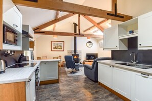 A modern kitchen with a dining area, a fireplace, and a living room with a sofa and TV. - 2 Bed in Seahouses (oc-gd1314) (Seahouses)