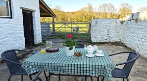 A table set outdoors with a checkered tablecloth, a potted plant, a teapot, cups, and a glass pitcher. - 2 Bed in Llangynidr (oc-l31914) (Llangynidr)