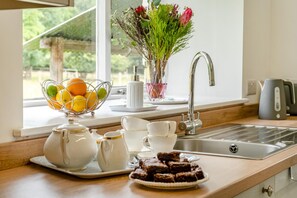 Une cuisine avec un évier, un panier de fruits, un vase de fleurs et une assiette de brownies.
