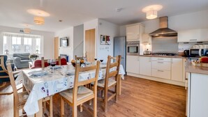Une cuisine moderne avec des meubles en bois, une hotte en acier inoxydable et un coin repas avec une table dressée pour quatre personnes.