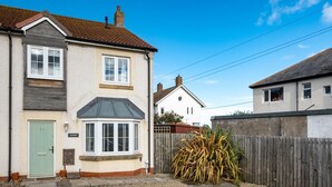 Une maison à deux étages avec une baie vitrée, une porte verte et une clôture en bois.