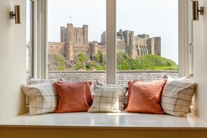 Une chambre avec vue sur un château, grâce à de grandes fenêtres.