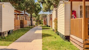 Uma fileira de casas móveis, com um caminho pavimentado entre elas, cercada por árvores.