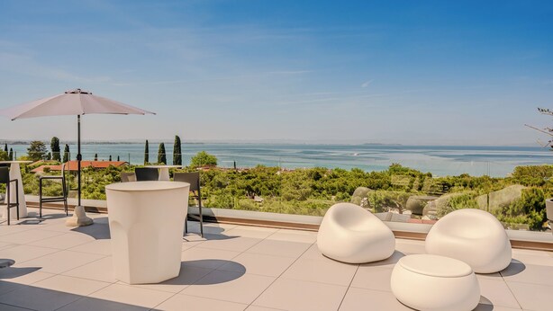 Um terraço com área de estar ao ar livre, uma mesa e um grande guarda-sol.