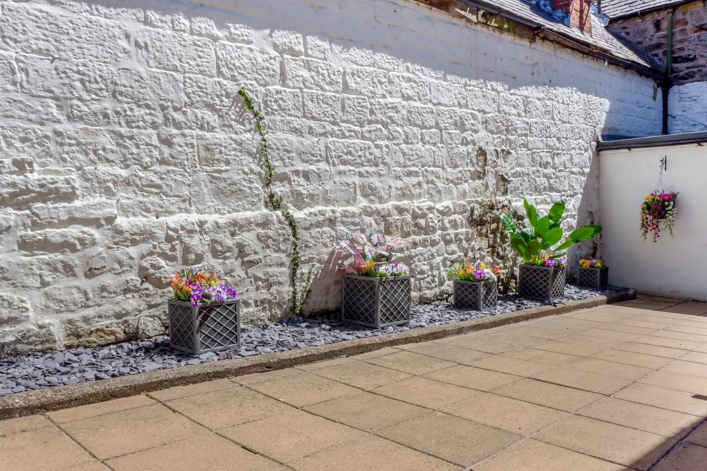 A white stone wall with potted plants and flowers.