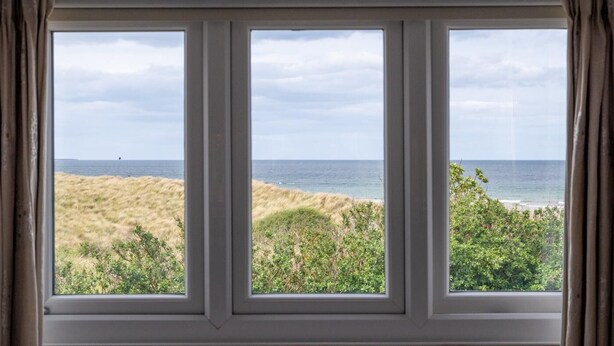 A window with a view of the beach and ocean. - 4 Bed in Bamburgh (oc-gd1264) (Bamburgh)