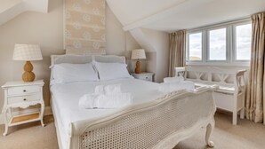 A bedroom with a large bed, two bedside tables, a desk, and a window with curtains. - 4 Bed in Bamburgh (oc-gd1264) (Bamburgh)