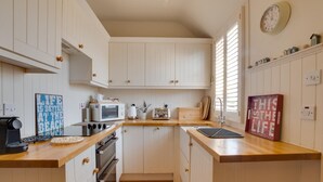 A compact kitchen with white cabinets, a microwave, a toaster, and a sink. - 2 Bed in Bamburgh (oc-gd1345) (Bamburgh)