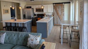 Una cucina moderna con isola centrale, sgabelli da bar e un divano con cuscini floreali.