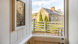 Une pièce avec vue sur un bâtiment en pierre et une clôture en bois.