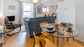 A modern living room with a sofa, dining table, chairs, and a TV.