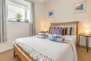 A bedroom with a bed, bedside tables, a window with curtains, and a potted plant. - 1 Bed in St. Just (oc-h31976) (Cape Cornwall)