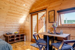 Un intérieur en bois comprenant une table à manger, des chaises, un banc et une fenêtre donnant sur un paysage agréable.