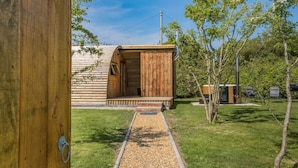 Een houten chalet met een veranda, omgeven door een gazon en bomen.
