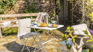 An outdoor seating area with a table set for breakfast, including croissants and coffee. - 3 Bed in St. Teath (oc-r31945) (Saint Teath)