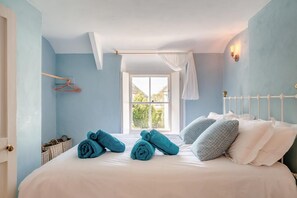 Ein Schlafzimmer mit Bett, Fenster und Pendelleuchte.