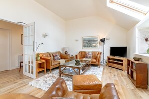A spacious living room with a sofa, ottoman, coffee table, and a television. - 2 Bed in Waren Mill (oc-gd1324) (Waren Mill)