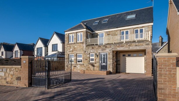 A two-story house with a stone facade, a garage, and a gated entrance. - 4 Bed in North Sunderland (oc-gd0238) (North Sunderland)