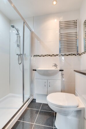 A modern bathroom with a glass-enclosed shower, a white sink, and a toilet. - 4 Bed in North Sunderland (oc-gd0238) (North Sunderland)