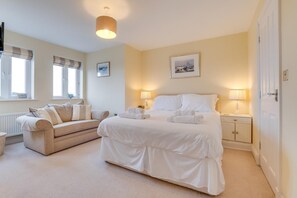 A bedroom with a bed, a sofa, and two bedside tables with lamps. - 4 Bed in North Sunderland (oc-gd0238) (North Sunderland)