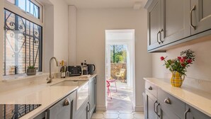 Een moderne keuken met een groot raam, een inbouwoven en een eethoek met een tafel en stoelen.
